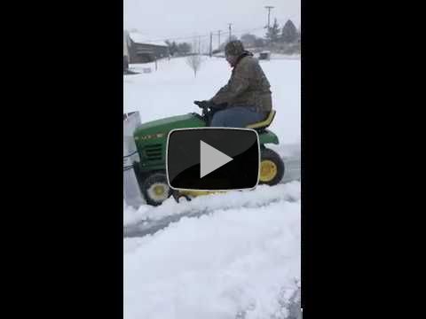Man plows snow with lawnmower and cardboard box