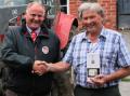 Merfyn Edwards (right) receives a celebratory bottle of whisky from Terry Hughes, managing partner of HJR Agri (Oswestry) Ltd, after purchasing the 100th McCormick tractor supplied by the dealership.