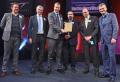 Quadron's Ben Binnell (3rd from left) and Ian Fleming (far left) with clients from the Royal Borough of Kensington and Chelsea, accepting the award from Will Carr of sponsors Ransomes Jacobsen (second from right) and comedian Hugh Dennis (far right)